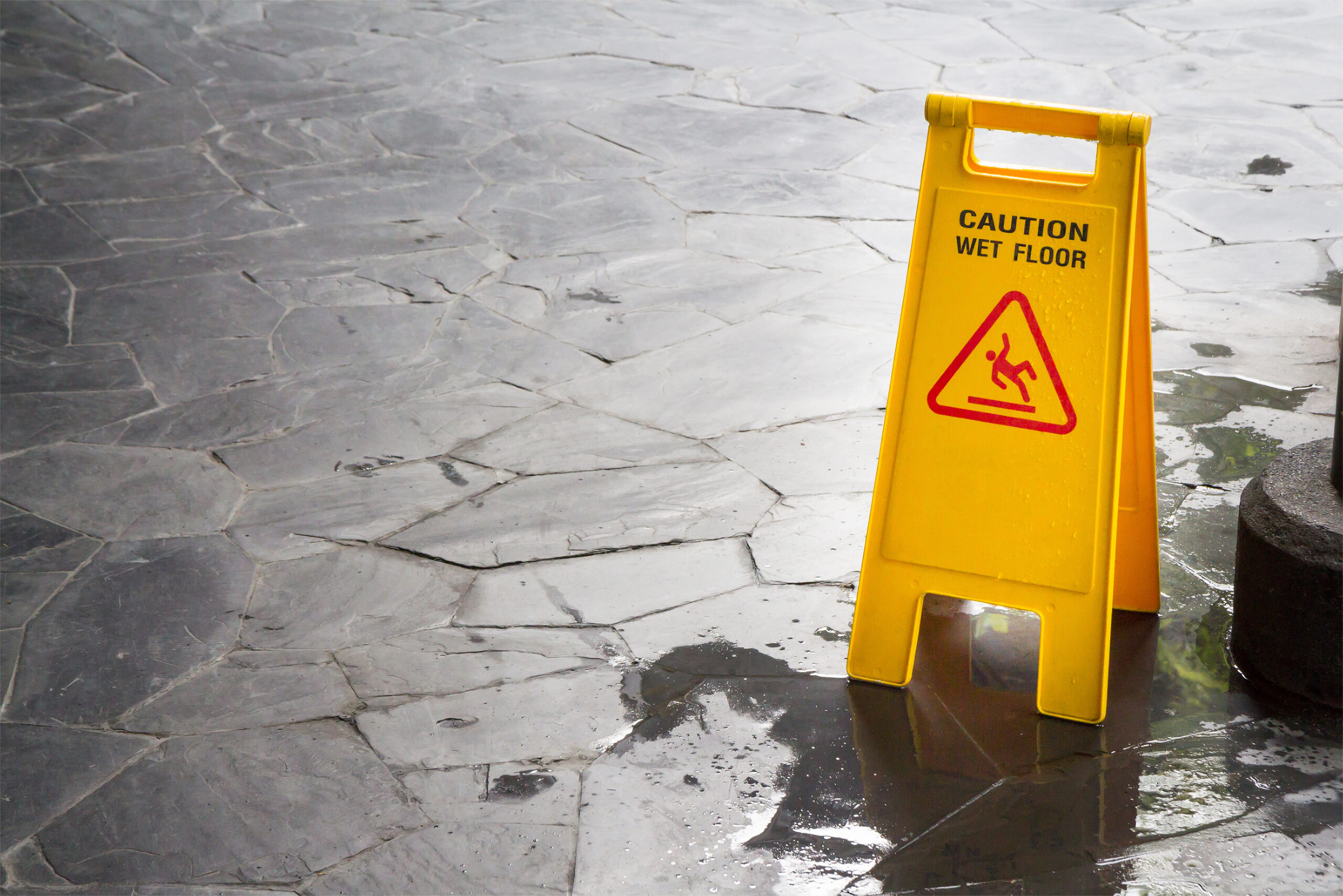 wet floor sign with water drops on wet stone floor